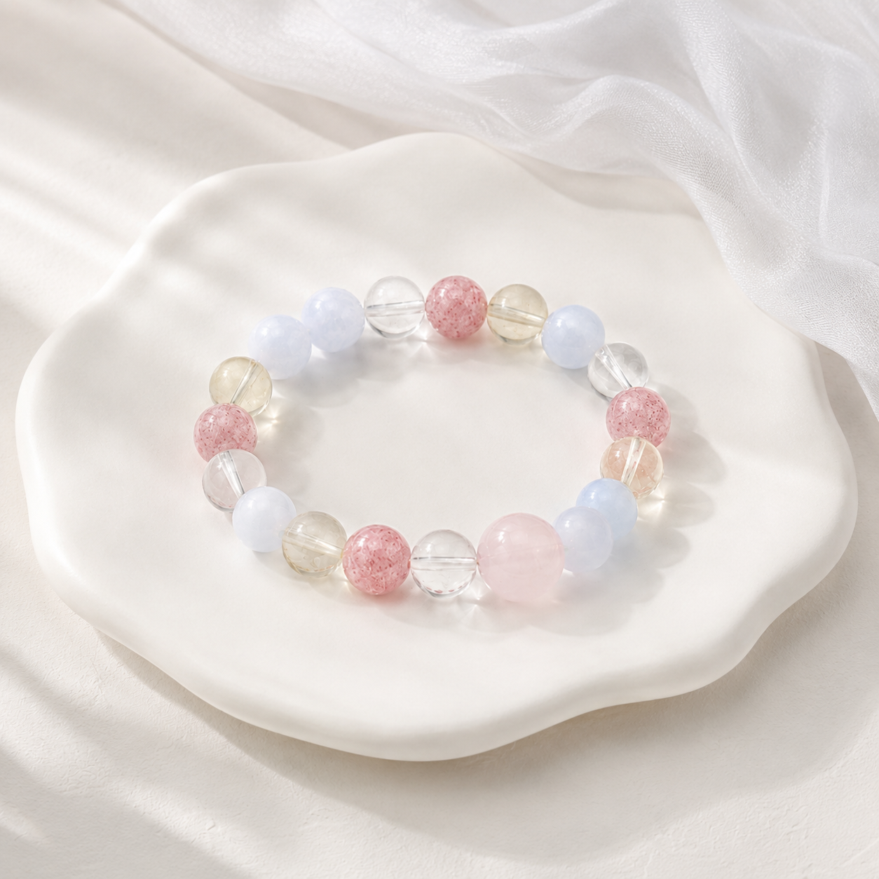 Pastel multi-gem stretch bracelet on white ceramic flower tray with silk background