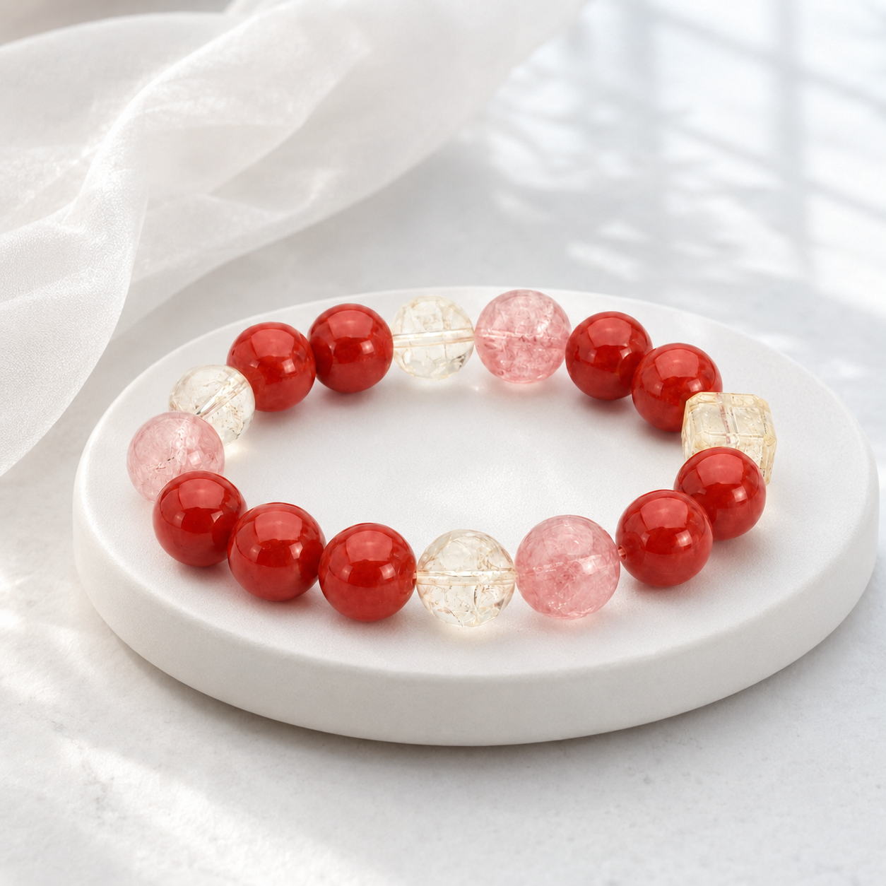 Red agate and crystal stretch bracelet on white marble tray with silk background