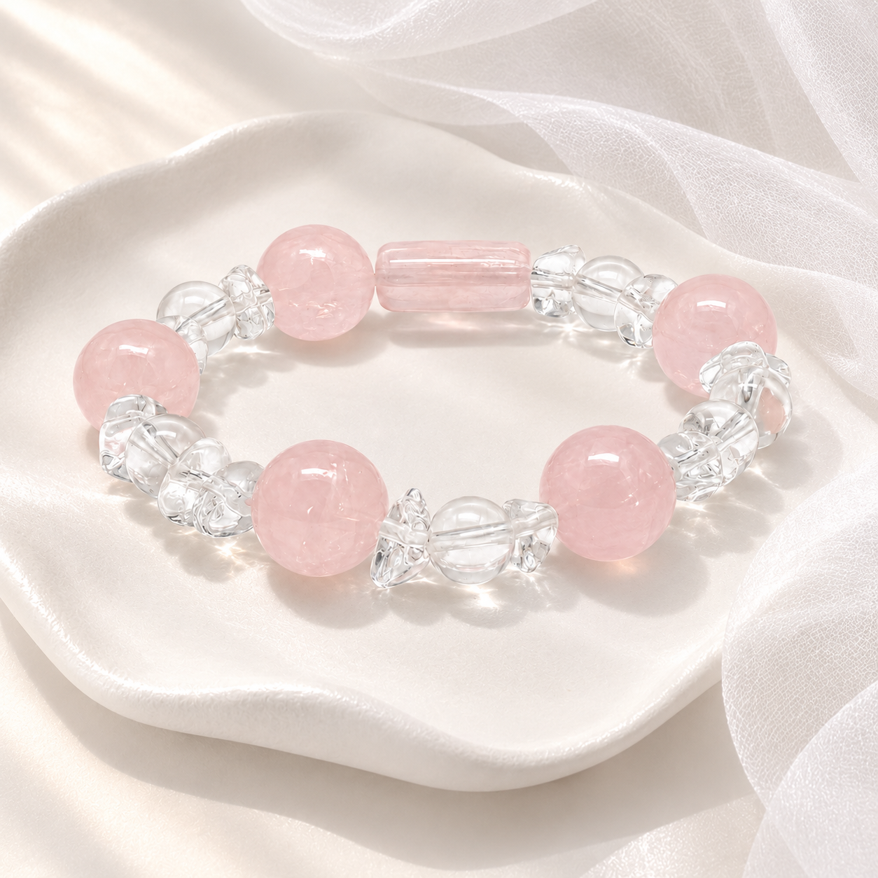 Rose quartz and clear crystal stretch bracelet on white silk tray flatlay